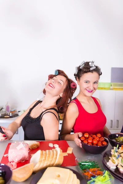 Zwei junge hübsche Hausfrauen kochen mit Lockenwicklern auf Haaren — Stockfoto