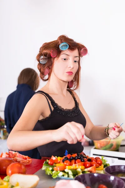 Молодая красивая женщина домохозяйка готовит с бигуди на волосах — стоковое фото