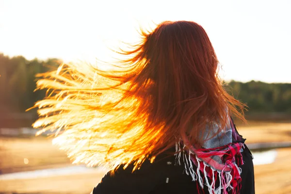 Donna con i capelli rossi divertirsi sul costo alla luce del sole — Foto Stock