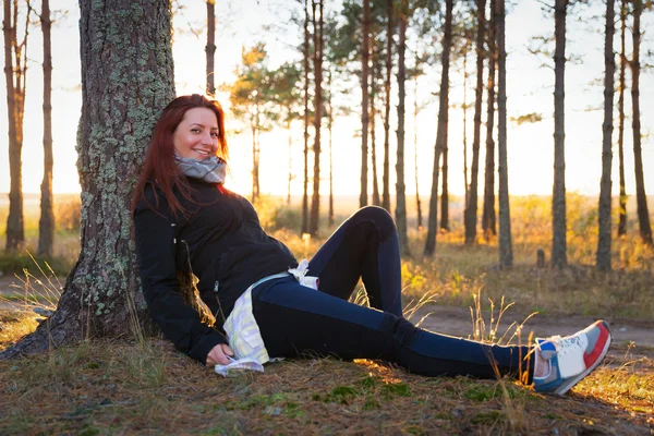 Mulher em um pôr do sol ilumina na floresta de outono — Fotografia de Stock