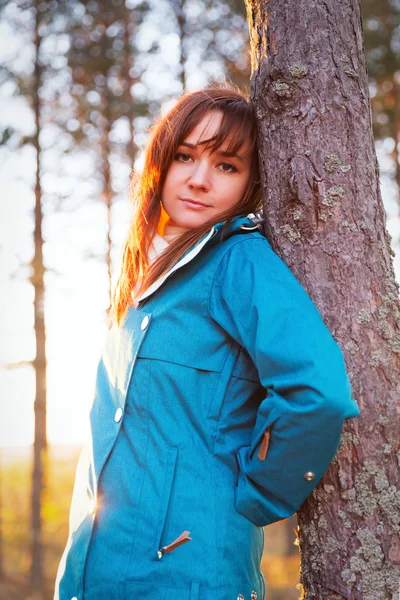 Mulher em um pôr do sol ilumina na floresta de outono — Fotografia de Stock