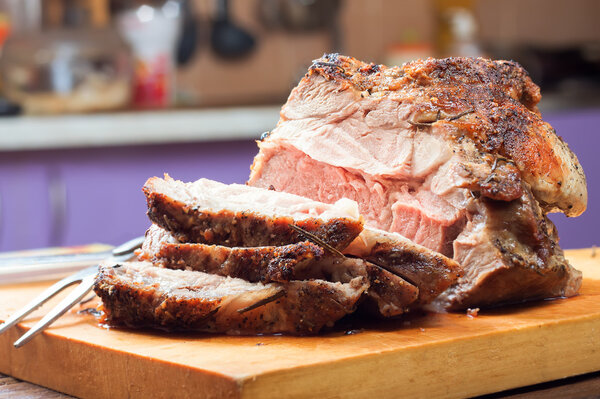 Grilled meat sliced with spices on a cutting board in the kitchen background