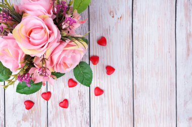 Beyaz ahşap arka planda pembe güller ve sevgililer günü kalpleri. Üst görünüm, kopyalama alanı olan düz uzanma