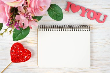 Pembe güller buketi ve kağıt not defterli sevgililer günü kalpleri ve beyaz ahşap arka planda seni seviyorum. Üst görünüm, kopyalama alanı olan düz uzanma