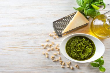 Beyaz ahşap arka planda yemek malzemeleriyle ev yapımı pesto sosisi.