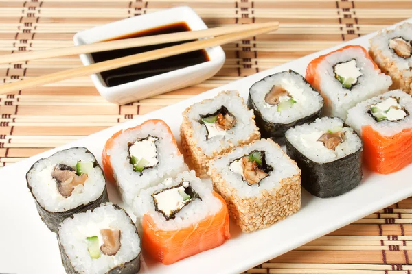 Sushi assortiment op wit schotel op bamboe achtergrond. — Stockfoto