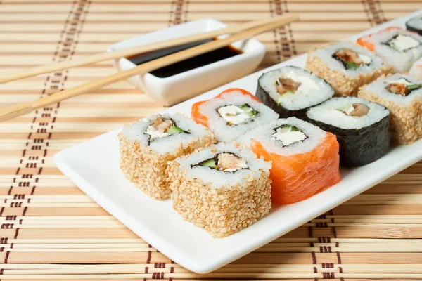 Sushi assortiment op wit schotel op bamboe achtergrond. — Stockfoto