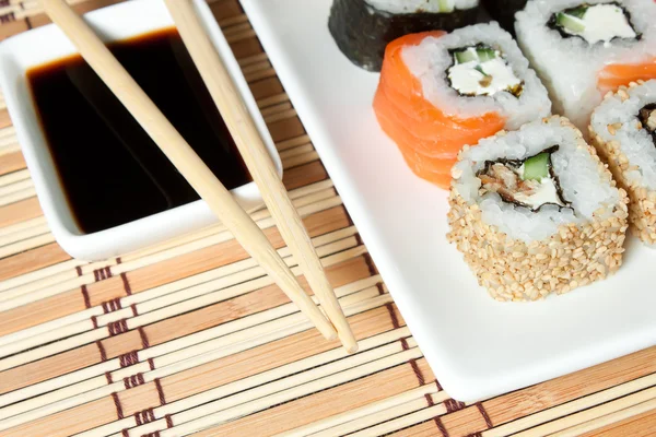 Sushi assortiment op wit schotel op bamboe achtergrond. — Stockfoto