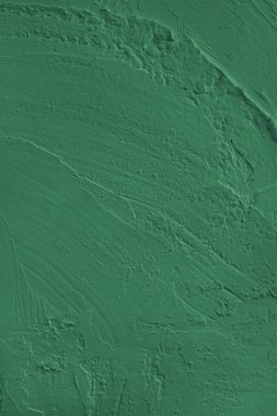 Close up, macro of vibrant green colored cement wall surface with rough, heavily textured, and abstract plaster strokes. Grunge background, industrial backdrop, modern wallpaper, design element.