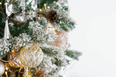 Karlı, şekerli Noel ağacı dalları, şenlikli ışıklar, dekoratif altın ve gümüş süslemeler. Parlak süslemeleri ve sıcak ışıkları olan tatil ruhu. Duvar kağıdı, arkaplan, arkaplan