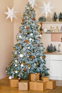 Altın ve beyaz süsler ve hediyelerle süslenmiş Noel ağacı, paketlenmiş hediye kutuları. Kış tatili temaları ve mevsimlik projeler için harika bir iç mekan..