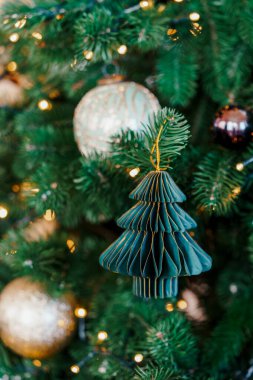 Yeşil Noel ağacı süsü ladin dalında parlayan ışıklar ve dekorasyonlarla sarkıyor kış tatillerinin büyülü ruhunu ve şenlikli ev dekorunu yakalıyor..