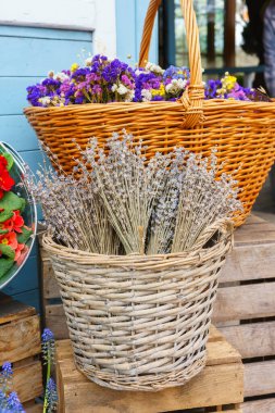 Açık hava çiçekçisinde kurutulmuş lavanta ve renkli bahar çiçekleriyle dolu bir sepet. Doğal dokular, çiçek pazarı atmosferi, mevsimsel dekor ve botanik detayları.