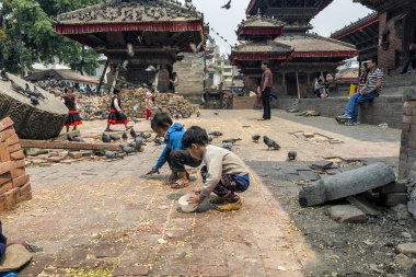 Katmandu, Nepal - 13 Nisan 2016: Tanımlanamayan çocuklar güvercinler Durbar Square Bhaktapur olarak kuru Mısır ile büyük depremden sonra 2015 yılında besleniyor.