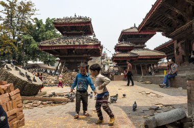 Katmandu, Nepal - 13 Nisan 2016: Tanımlanamayan çocuklar güvercinler Durbar Square Bhaktapur olarak kuru Mısır ile büyük depremden sonra 2015 yılında besleniyor.