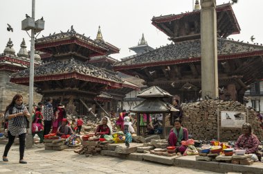 Katmandu, Nepal - 13 Nisan 2016: Kuru mısır kuş beslemek hasarlı Katmandu Durbar Meydanı olarak büyük depremden sonra 2015 yılında satış kimliği belirsiz kadın. Durbar Square Bhaktapur şehir merkezi var. Tapınaklar, Müze ve Kraliyet Sarayı l nerede olduğunu