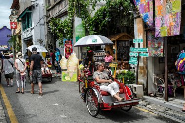 Ermeni Caddesi 'ndeki turistler, birçok turistik etkinliğe sahip bir miras yolu, Penang, Malezya - popüler ulaşım araçlarından biri olan rikşovunu kullanan yerel vatandaş.