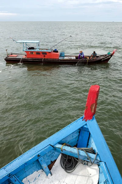 身份不明的渔民正在把渔网从海上拖到马来西亚普劳凯塔姆的渔船上 — 图库照片