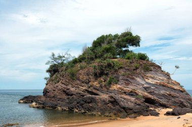 Dramatik kayalık uçurumların manzarası, sakin bir kumsal ve Pantai Kuala Kemasik, Terengganu, Malezya 'da açık tropikal bir gökyüzü altında sakin bir mavi deniz.