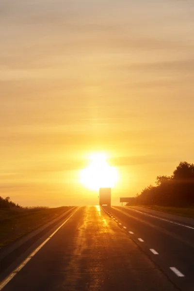 Trucking at sunrise on an empty road — Stock Photo, Image