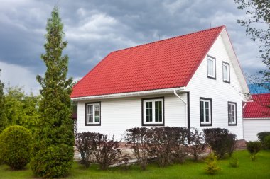 Bahçe ve karanlık bulutlar ve kır evi kırmızı çatılı