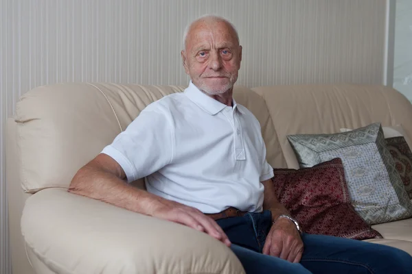 Smiling old man sitting on sofa — Stock Photo, Image