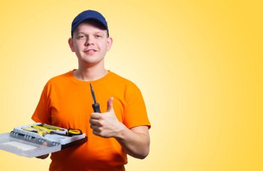 Gülümseyen ve baş parmağını gösteren aletleri olan tamirci.