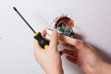 Elektrikçi duvardaki kırık bir soketi tamir ediyor.