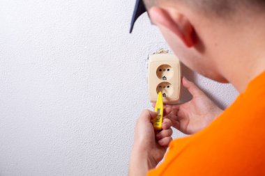 Elektrikçi duvara bir soket takıyor.
