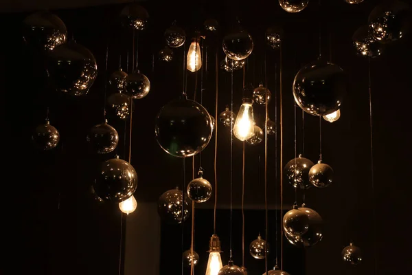 Eski tozlu parlak lambalar telin üzerindeki ampuller karanlıkta parlıyor ve ayna topları etrafında parlıyor.
