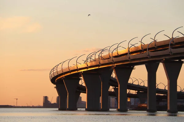 Orange solnedgång över floden med en motorvägsbro — Stockfoto