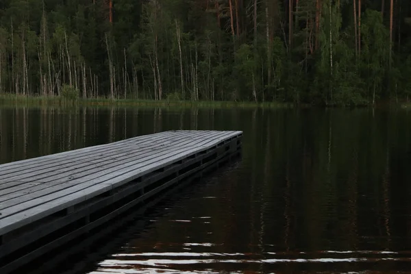 Деревянный пирс на лесном озере в сумерках. — стоковое фото