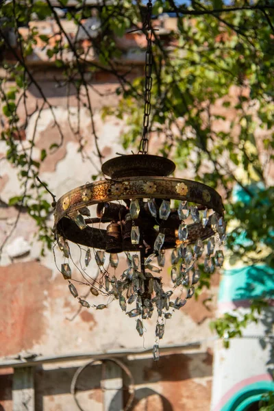 En gammal rostig ljuskrona med glashängen hänger på en trädgren — Stockfoto