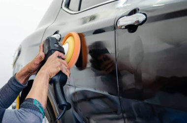 Cilalayan, arabaları kaplayan bir adam. Arabanın cilalanması arabanın yüzeyindeki kirleticilerin temizlenmesine yardımcı olacaktır..