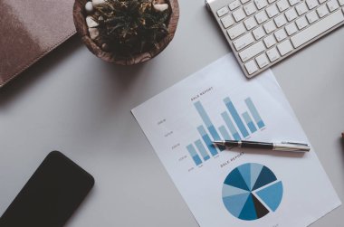 İş belgesi Finansal muhasebe grafikleri ve tablolar analizi masaüstünde klavye ve akıllı telefon. Ton klasiği - üst görünüm.