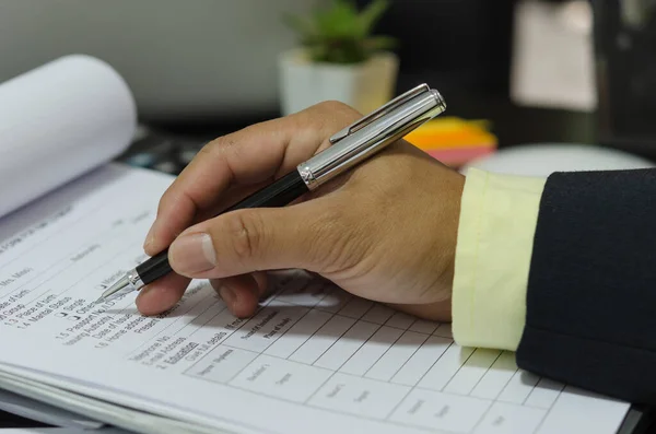 Hand with pen write application documents on desk.