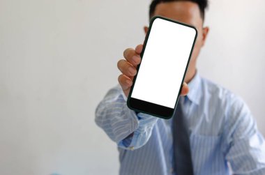 Adam elinde bir akıllı telefon tutuyor. Cep telefonu modeli beyaz ekran boş. Karşısında duruyor. Pazarlama reklamları ya da çevrimiçi ürünlerin tanıtımı için kullanılacak.