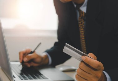 man holding a credit card and on the desk. Laptop computer.Online shopping business, pay by credit card or financial transactions and installment loan product.