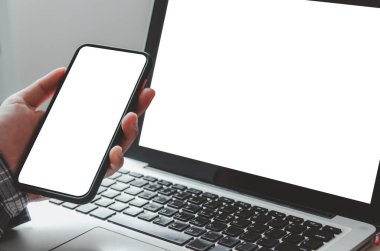 hand holding phone mockup image blank screen computer laptop  for advertising text in workplace desk at office.Clipping path