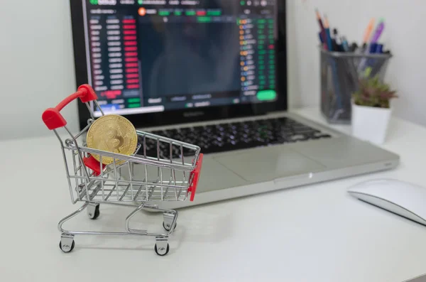 Digital Investment Bitcoin placed on a cart on desk and computer laptop.