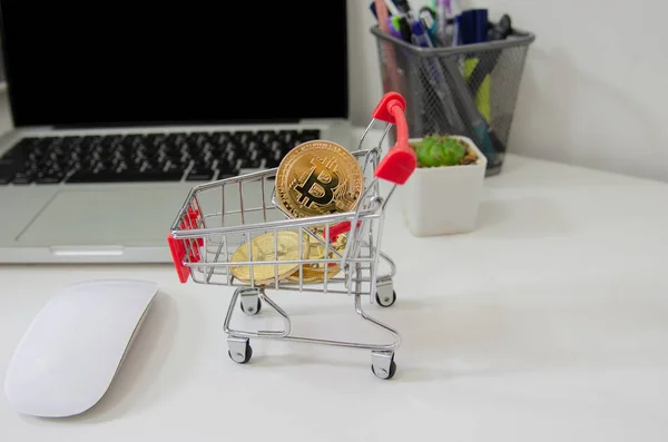 Digital Investment Bitcoin placed on a cart on desk and computer laptop.