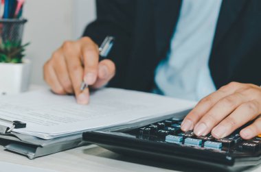 İş adamı masada hesap makinesi kullanıyor. İş finansmanı, vergi ve yatırım kavramları.