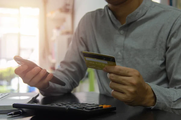 Man holding a credit card and a cell phone to pay for goods or services online or shopping online. concept financial business