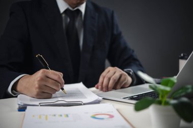 Masada dizüstü bilgisayarla kalem imzalama evrakları, sözleşme imzalama, önemli karar verme ve profesyonel bir ofiste kurumsal yönetim..