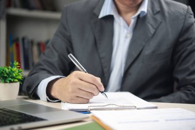 Ofiste resmi bir belgeyi inceleyen ve imzalayan bir iş adamı. Yasal anlaşma, iş sözleşmesi ve idari evrak imzalama kavramları için ideal.