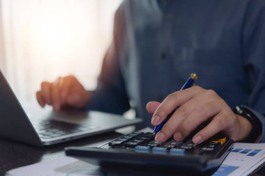 Hesap makinesi ve dizüstü bilgisayar kullanan muhasebeci. işletme finans planlaması masasında mali vergi belgeleriyle fatura, kalem ve teknoloji yönetimi maaşları online internet bankacılık konseptiyle.