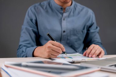 İş adamı kalemle yazılmış ve iş stratejisi, piyasa araştırması veya yatırım planına işaret eden bir belge üzerindeki mali veri ve grafikleri analiz ediyor. Şirket finansmanı için ideal.