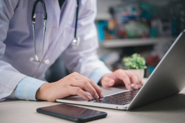 Ofiste dizüstü bilgisayar kullanan doktor, tıbbi kayıtlar, dijital sağlık yönetimi, online danışma, modern teletıp teknolojisi, hastane veri sistemi, profesyonel konsept üzerinde çalışıyor..