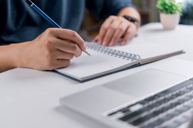 Kalemle deftere yazan kişi. Online eğitim, planlama, öğrenim kavramları ve yazılı belgelerin ve fikirlerin önemi.