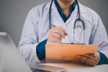 Sağlık ve tıp konsepti. Hasta muayene sonuçları için sağlık raporuna yazan bir doktor. Bir klinikte sigorta talebi, teşhis ya da tedavi protokolü için bilgi belgeleyen doktor.